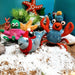 Felt sea creature ornaments on a sandy surface with plants and rocks.