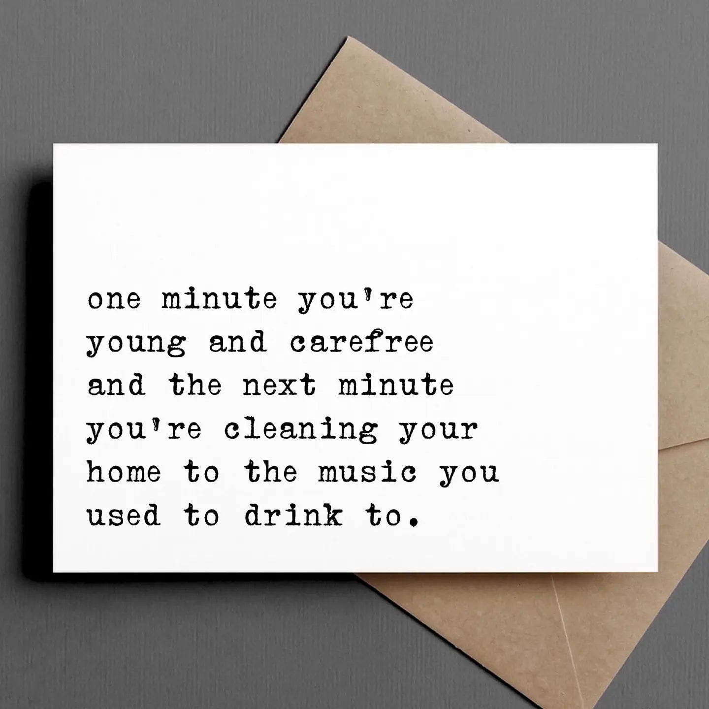 Ink & Attitude Card Collection illustrating a relatable greeting card with the text 'one minute you're young and carefree and the next minute you're cleaning your home to the music you used to drink to.' in a retro typewriter font.
