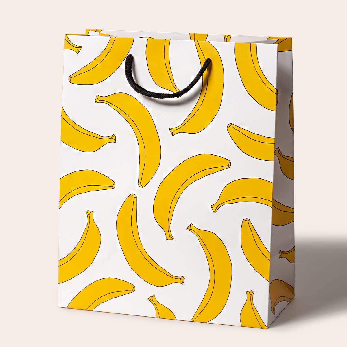 Vibrant gift bag featuring a playful banana print, designed by Seltzer Goods, perfect for any occasion. This Bananas Gift Bag is made of sturdy paper and has a comfortable cotton handle, ideal for wrapping up gifts.