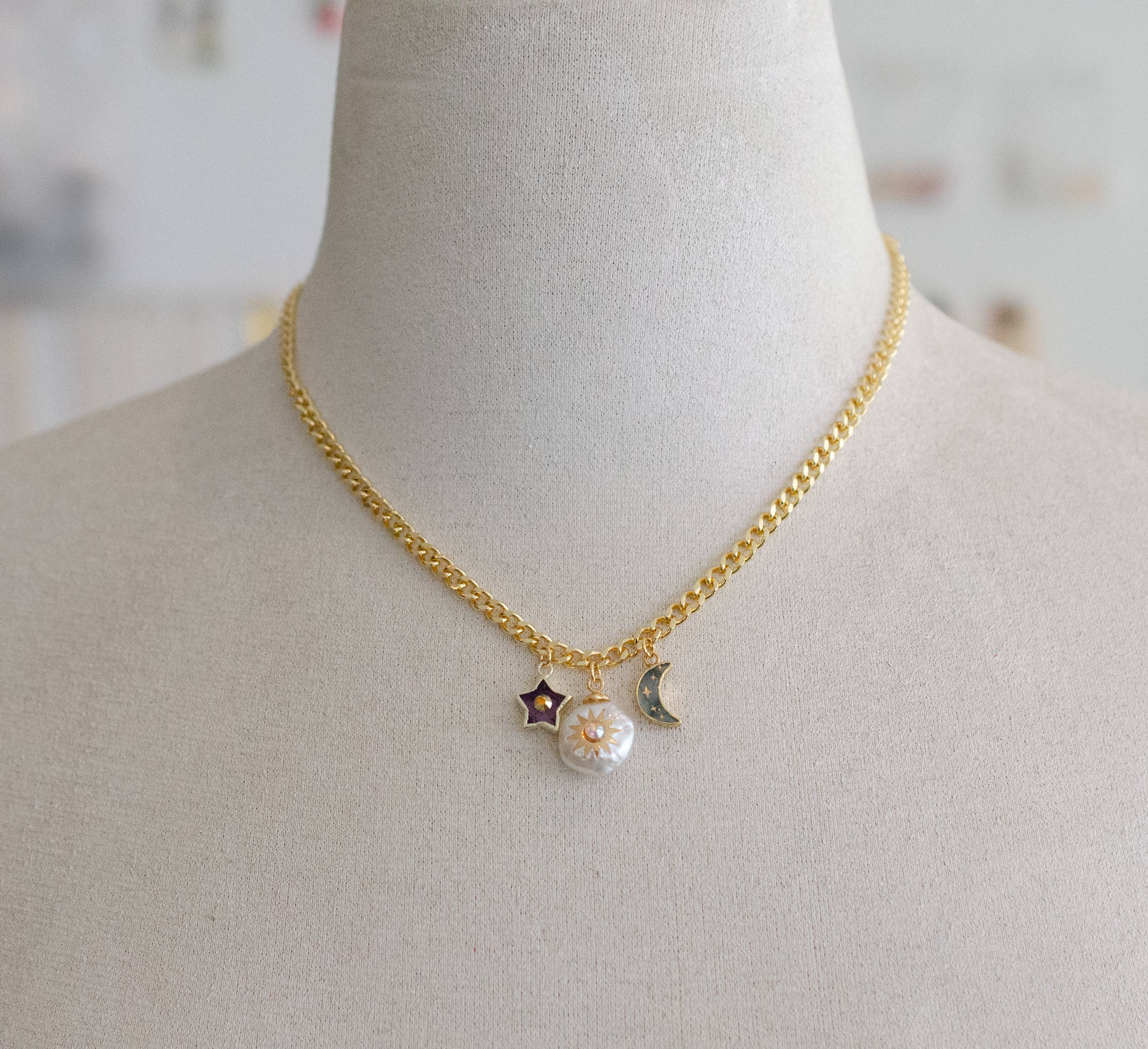 Gold curb chain necklace featuring celestial charms: an amethyst star, a pearl sun, and a labradorite moon by Jill Makes, titled 'Pearl and Moon Celestial Charm Necklace'.