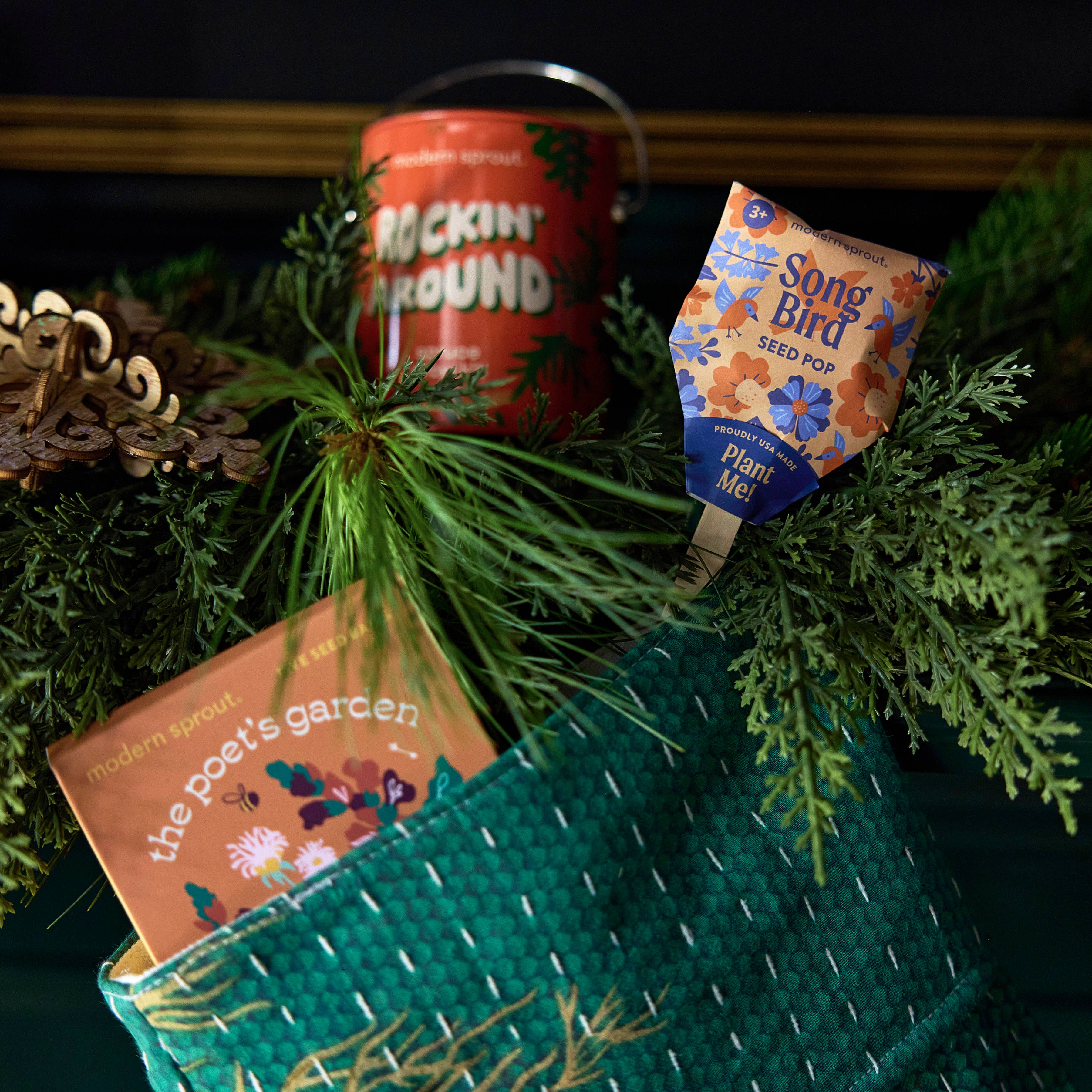 Song Bird seed pop displayed alongside holiday decorations within a green basket, showcasing the festive planting options from Modern Sprout.