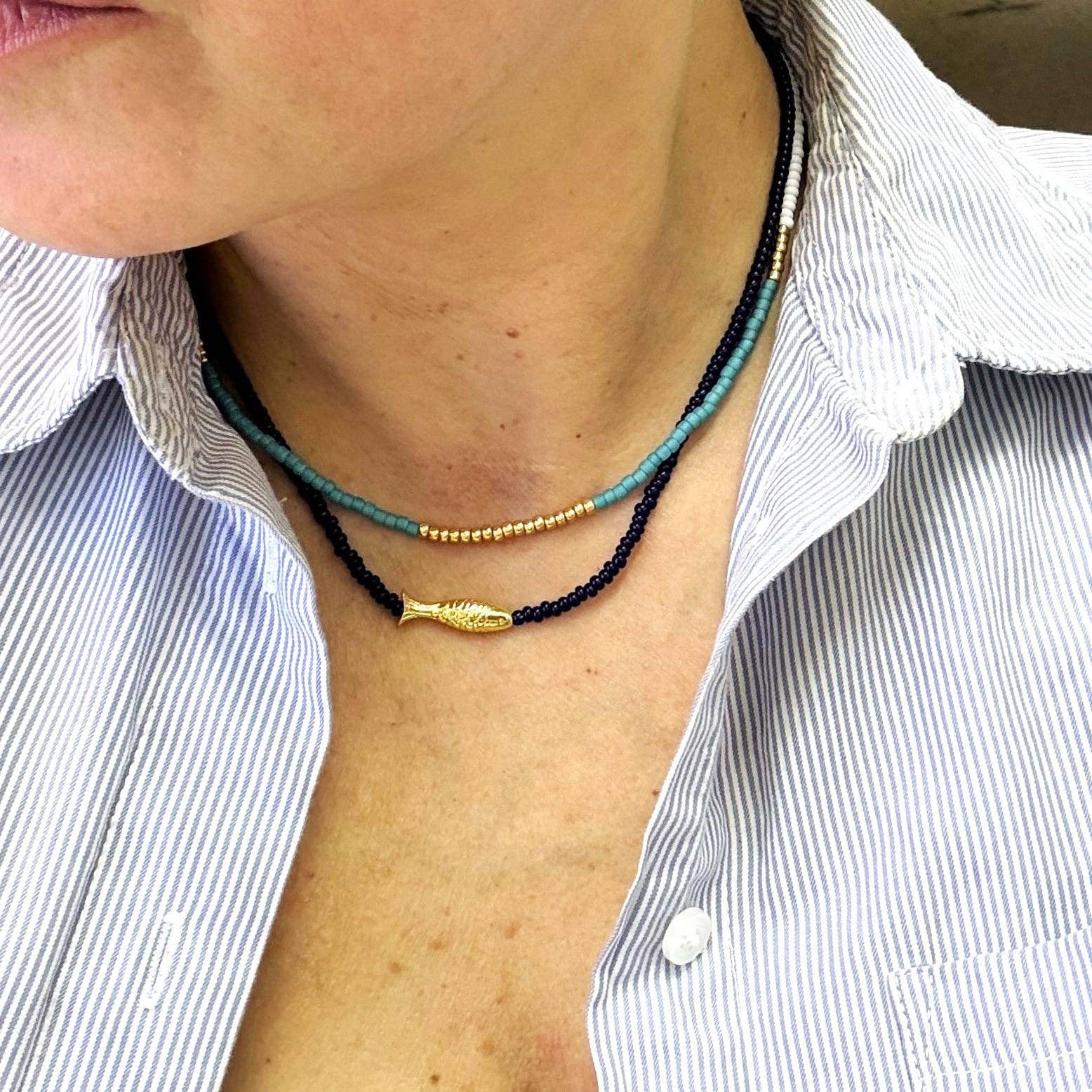 Lithe No. 2 Beaded Necklace by The Silver Wren, displayed layered on a model's neck, featuring colorful seed beads in shades of turquoise and navy, accentuated by a gold-filled clasp.