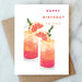 Colorful birthday card featuring two drinks garnished with citrus, wishing happy birthday, by Abigail Jayne Design, part of the Abigail Jayne Card Collection.