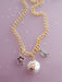 Stylish display of the Pearl and Moon Celestial Charm Necklace by Jill Makes, highlighting the unique gold-detailed charms including an amethyst star, a shining pearl sun, and a labradorite moon on a delicate chain.
