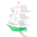 White and green Sailing Ship Kite by Haptic Lab, being held by a person, showcasing its handmade quality and elegant design.
