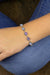 Silver bracelet with purple beads on a wrist against a blue jeans background
