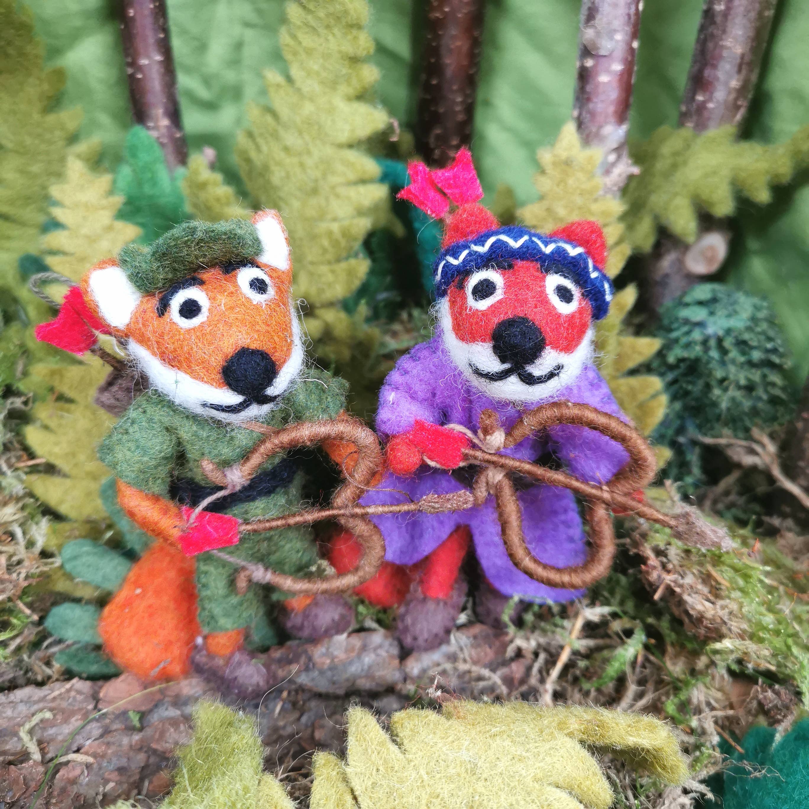 Two felted animal figures, a fox and a rabbit, holding hands in a forest setting.