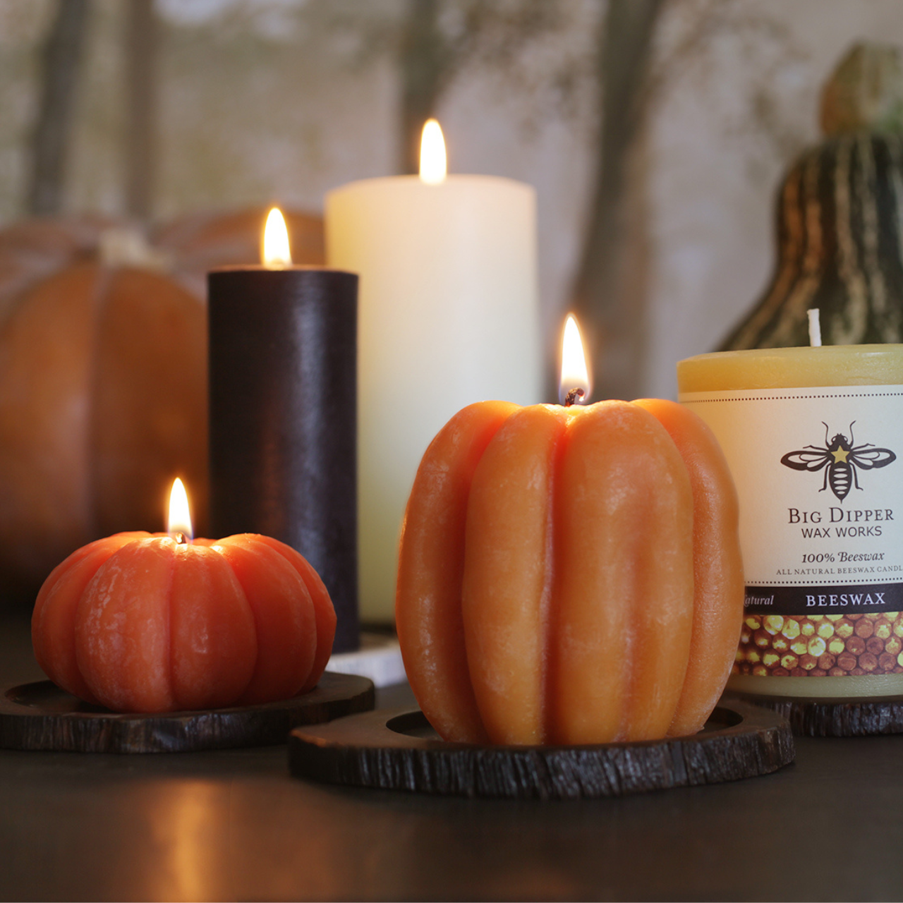 Pumpkin-shaped candles and other candles on a wooden surface 