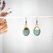 Turquoise Dipped Oval Gold Earrings displayed elegantly by The Artifact House, featuring a unique handmade design with a turquoise glaze and luxurious 24K gold accent.