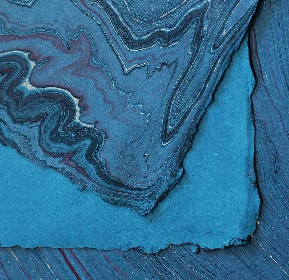 Hand marbled paper in shades of blue, showcasing unique patterns, created by The Casual Bookbinder for the Softcover Notebook.