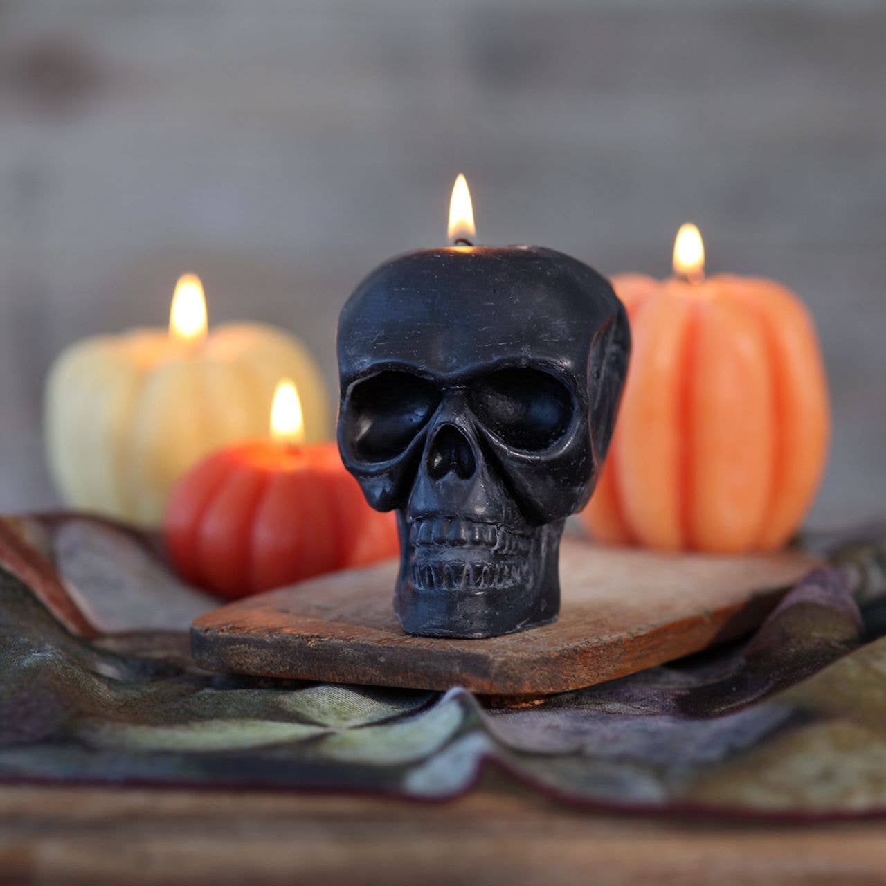 Skull-shaped candle with pumpkins and other candles