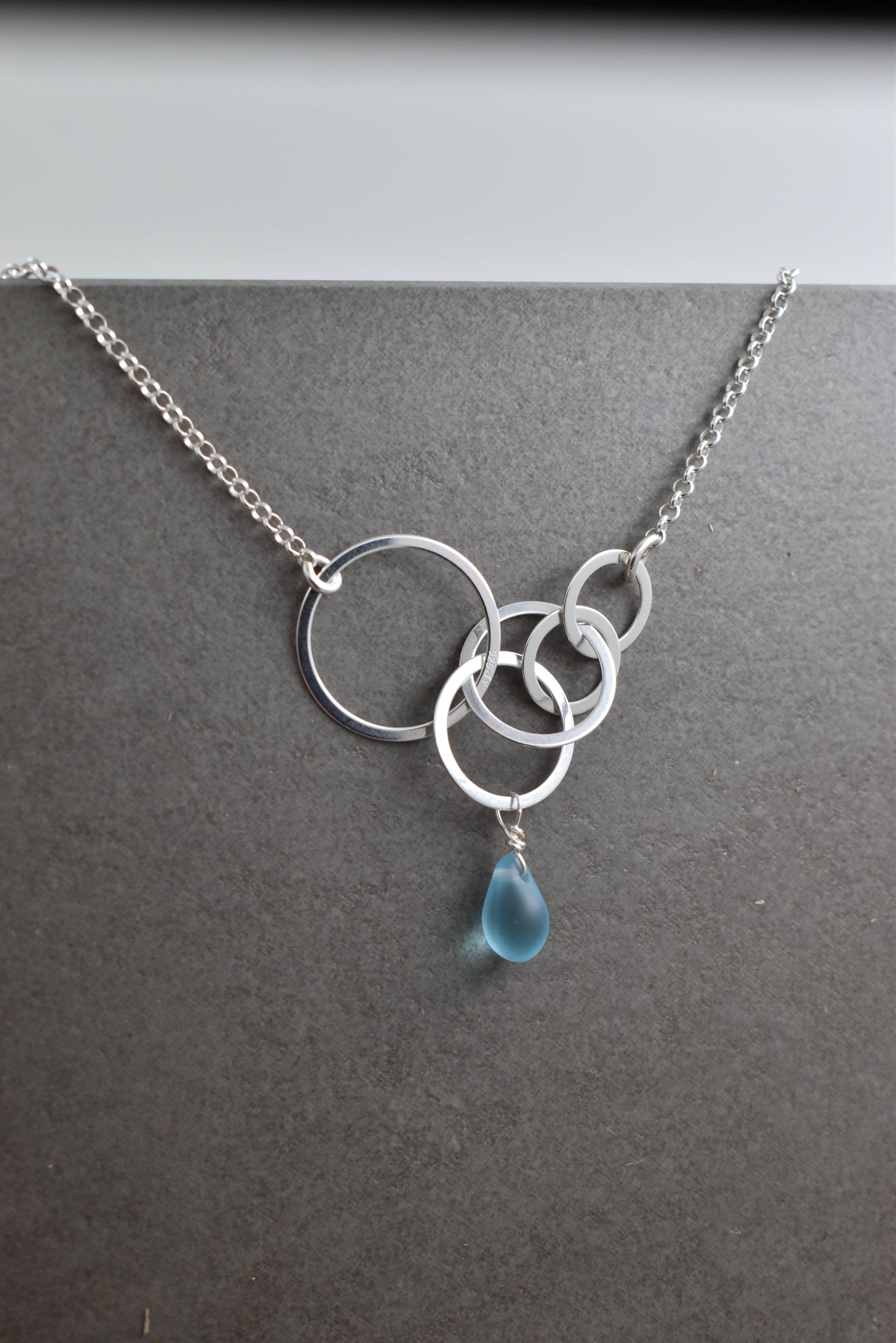 Aqua Eco Glass Sterling Silver Circle Necklace featuring a beautiful aqua Eco Glass teardrop pendant with a frosted finish and delicate sterling silver circles, ideal for eco-conscious fashion lovers.