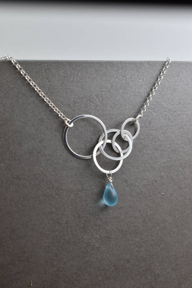 Aqua Eco Glass Sterling Silver Circle Necklace featuring a beautiful aqua Eco Glass teardrop pendant with a frosted finish and delicate sterling silver circles, ideal for eco-conscious fashion lovers.