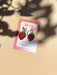 Mini Strawberry Acrylic Dangle Earrings by Sunnie Creative displayed on a branded card against a soft background with shadows.