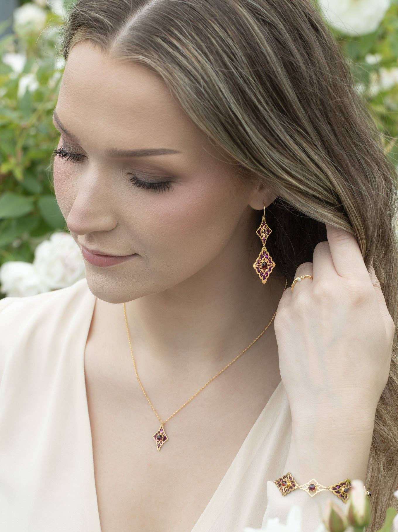 Esmeralda Earrings - A whimsical pair of 18K gold-plated earrings featuring garnet ovals and niobium florals, guaranteed to add sparkle and movement to any ensemble.