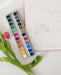 Close-up of the 24 Color Watercolor Paint Palette, featuring richly pigmented paints arranged in a stylish metal tin with a built-in mixing space.