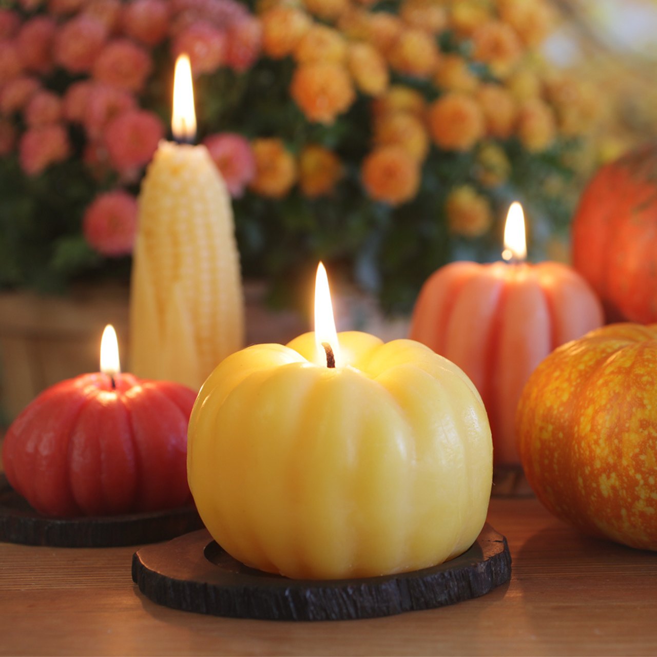 Decorative candles shaped like pumpkins  on a wooden surface 
