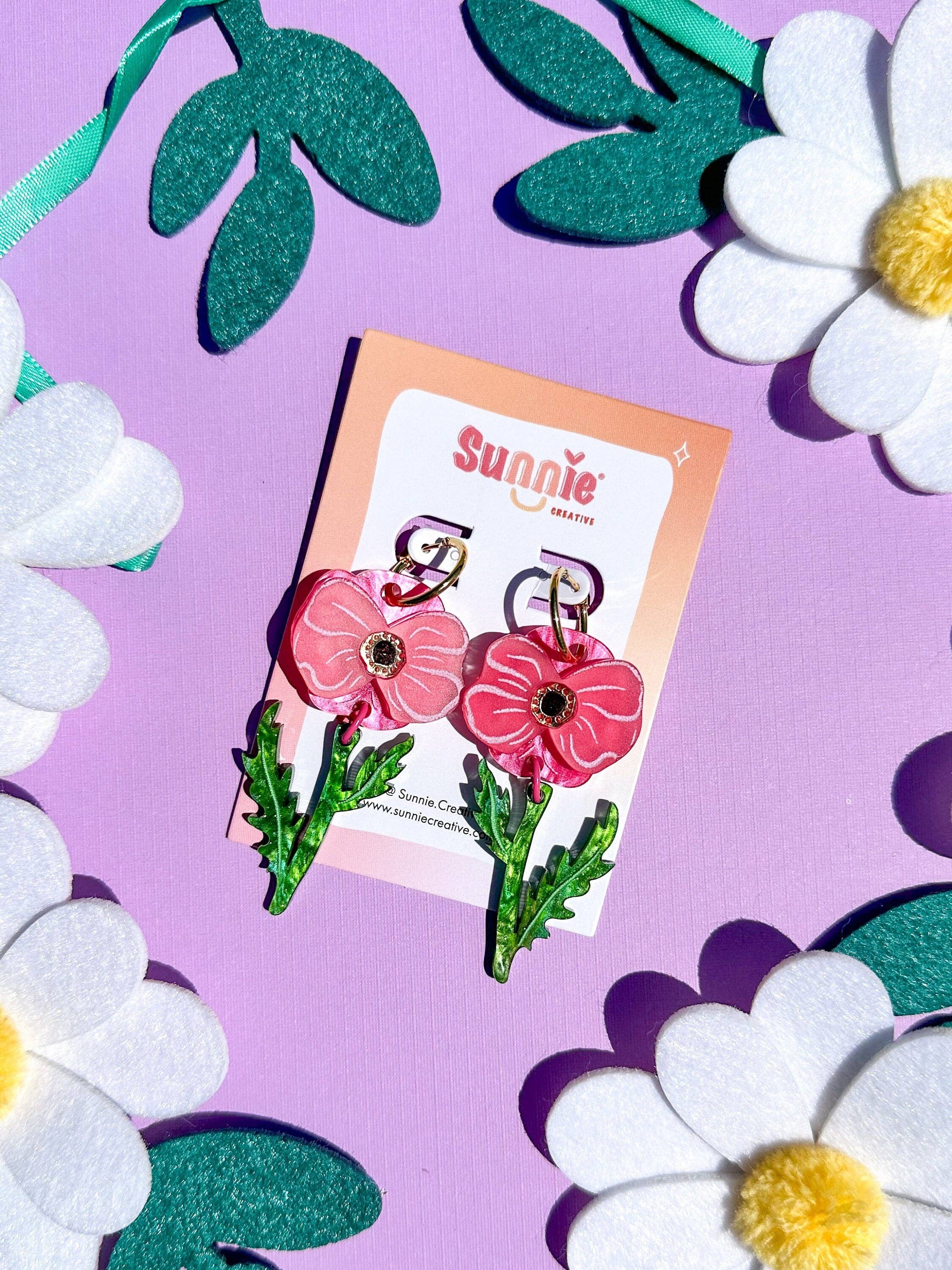Poppy Bloom pink flower earrings by Sunnie Creative presented on a vibrant backdrop with decorative felt flowers.