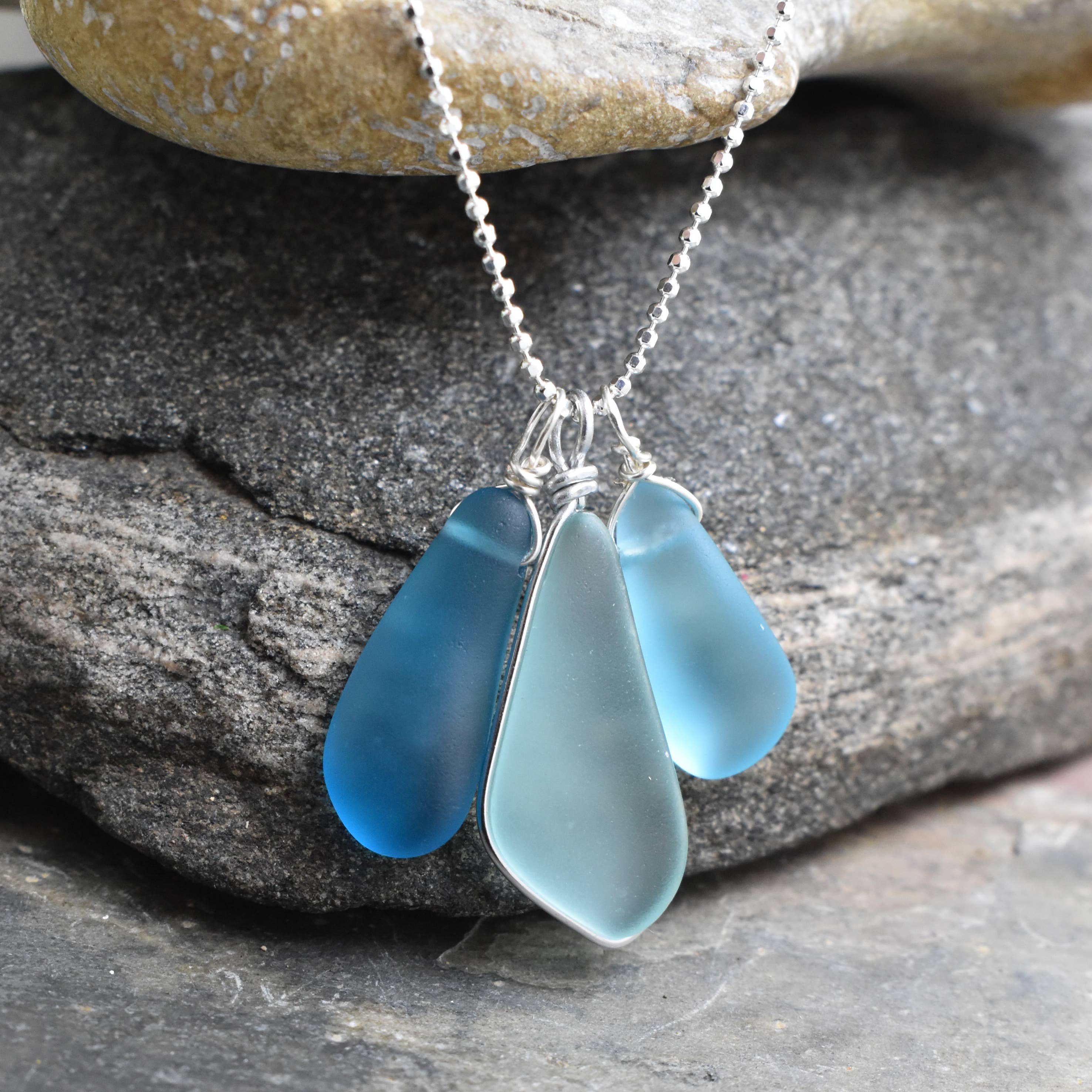 The Blue Eco Glass Trio Sterling Silver Necklace worn elegantly on a model, complementing a casual outfit with a touch of coastal charm.