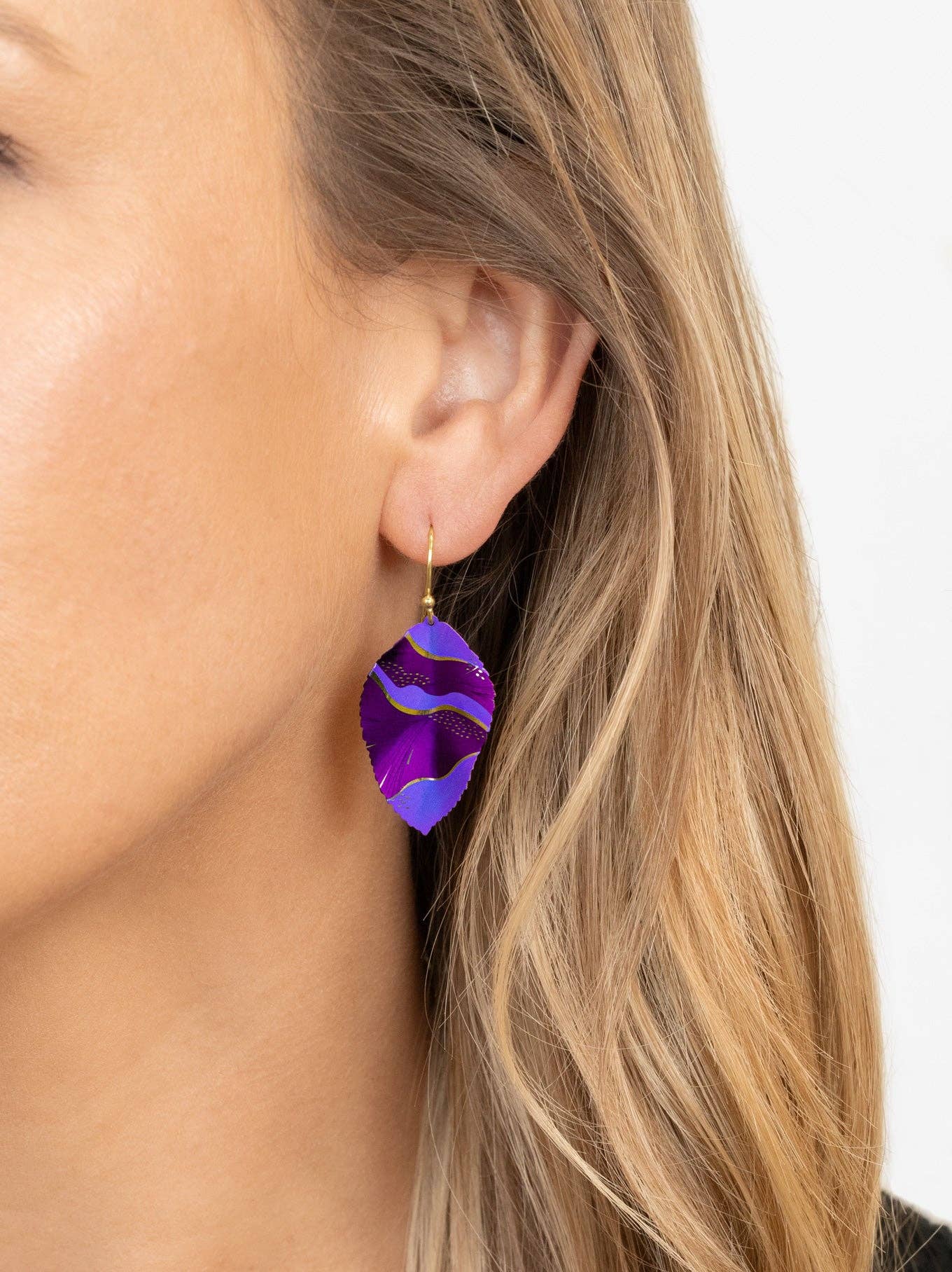 Close-up of Eccentric Elm Earrings, 18K Gold-plated niobium swinging in all their leafy glory - a fashionable way to show off your love for the great outdoors without getting your hands dirty.
