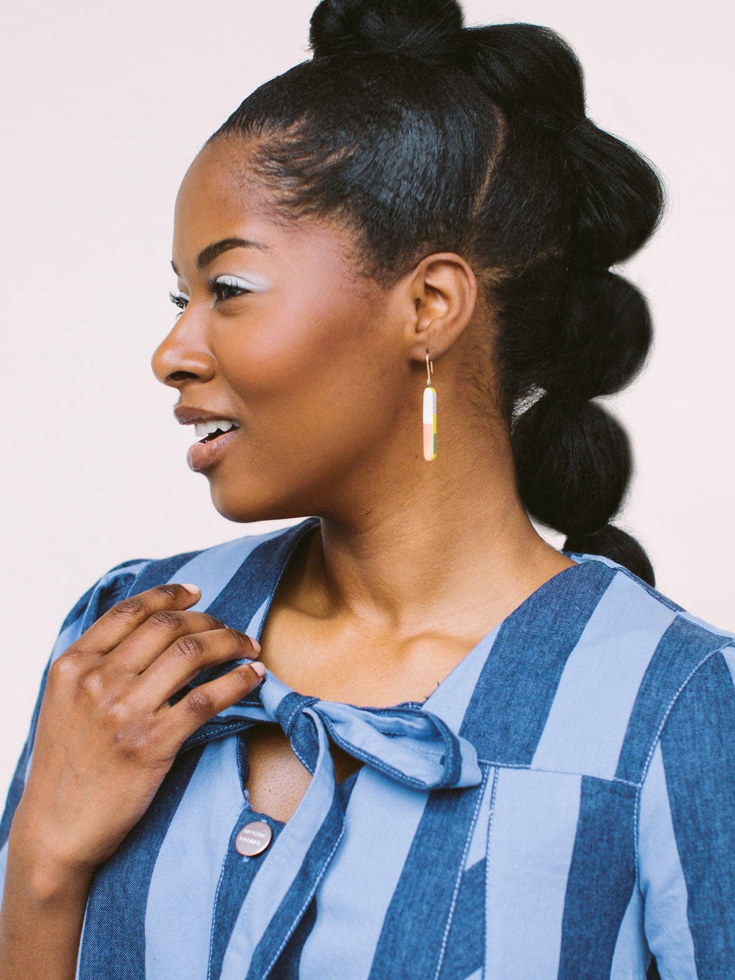 Model wearing Skinny Dip Earrings, showcasing the earrings' slender shape against a blue striped outfit, designed by Twenty Two West.