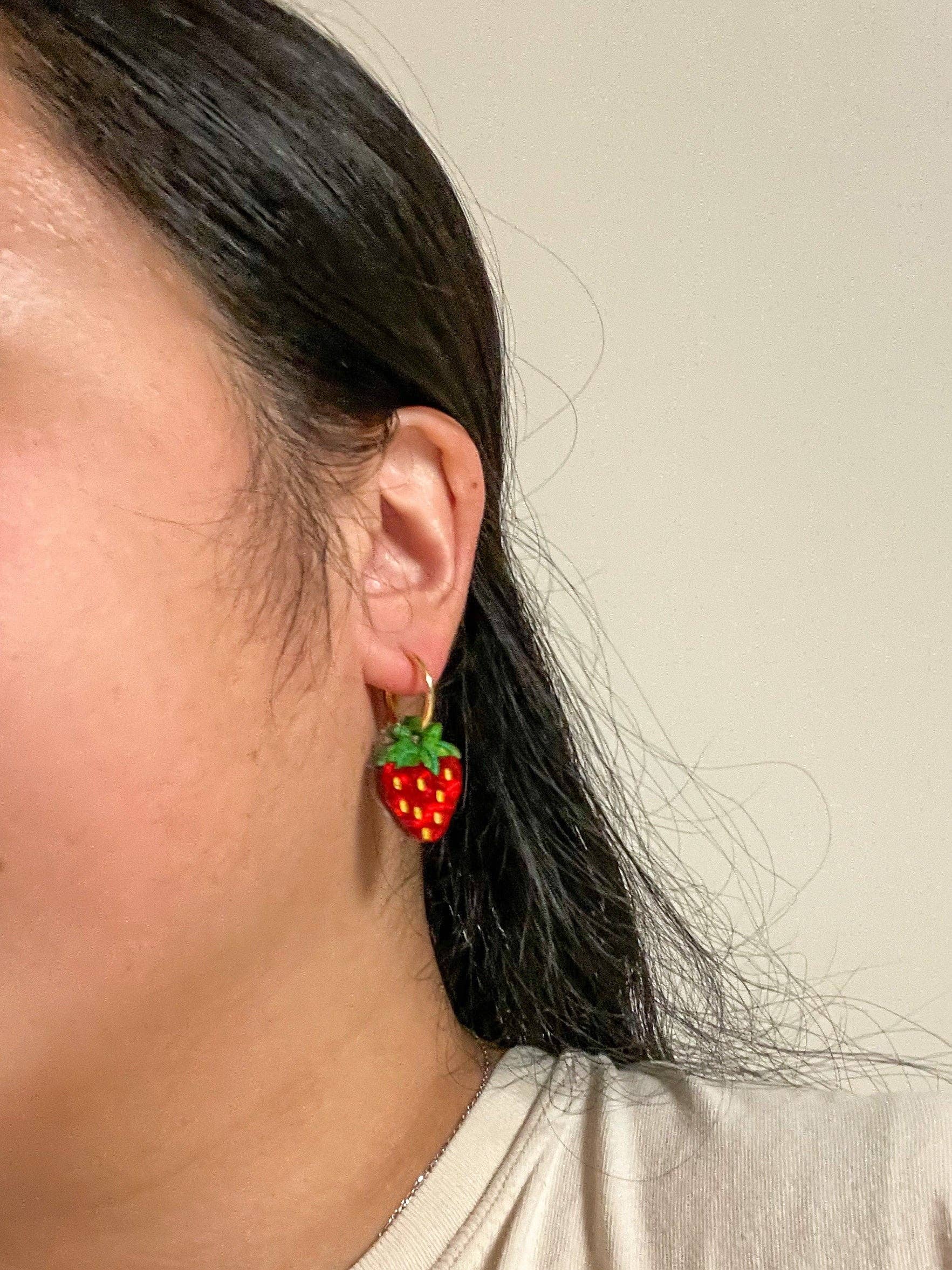 Close-up of Mini Strawberry Acrylic Dangle Earrings by Sunnie Creative worn by a person, highlighting the earring's design and colors.