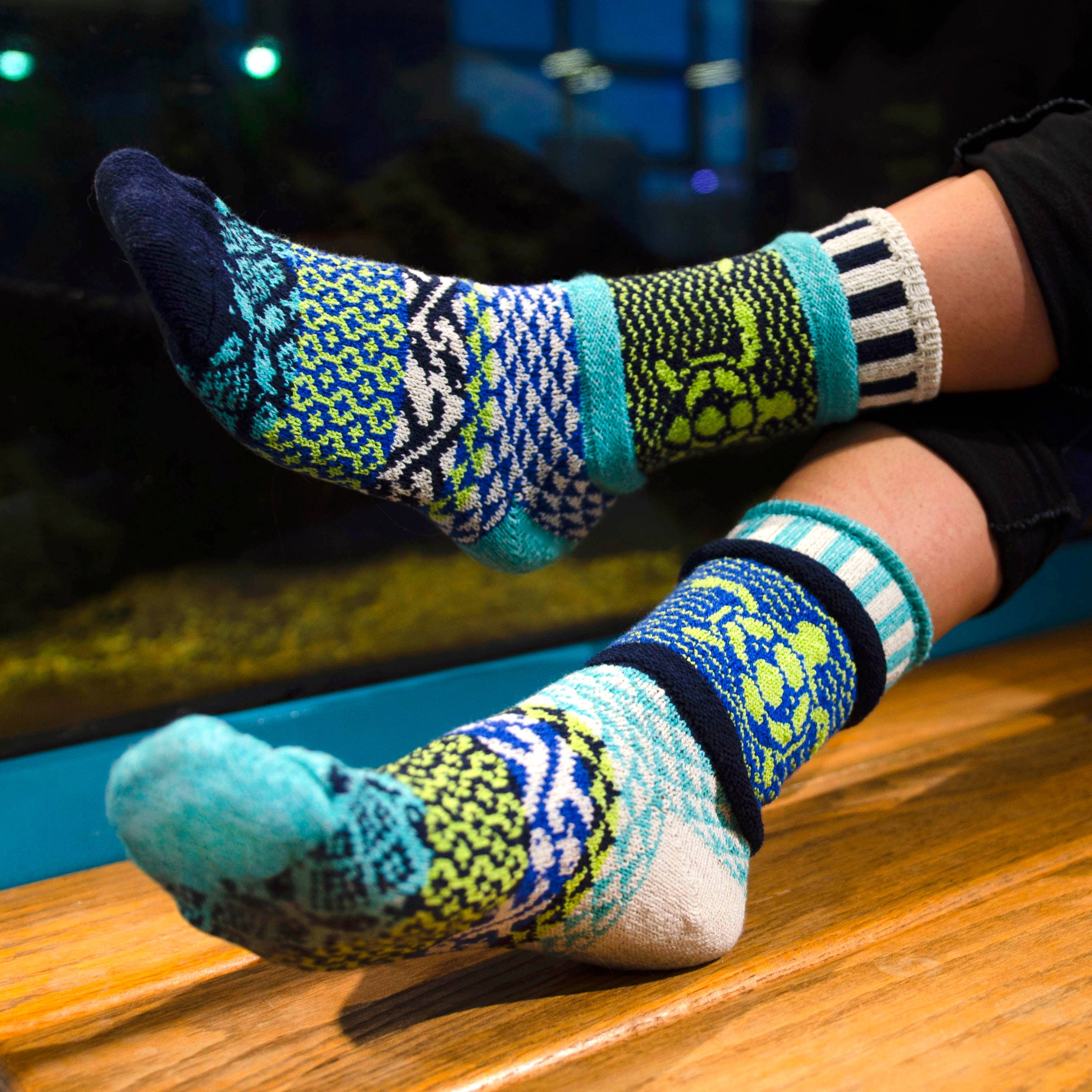 A pair of Ocean Crew Socks displayed on a sandy beach, representing support for ocean cleanup efforts.
