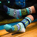 A pair of Ocean Crew Socks displayed on a sandy beach, representing support for ocean cleanup efforts.