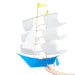 Colorful white and blue Sailing Ship Kite by Haptic Lab, held by a person, designed for soaring in the wind and enhancing home aesthetics.