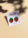 Mini Strawberry Acrylic Dangle Earrings by Sunnie Creative on a branded card, featuring vibrant colors and a playful design against a subtle background.