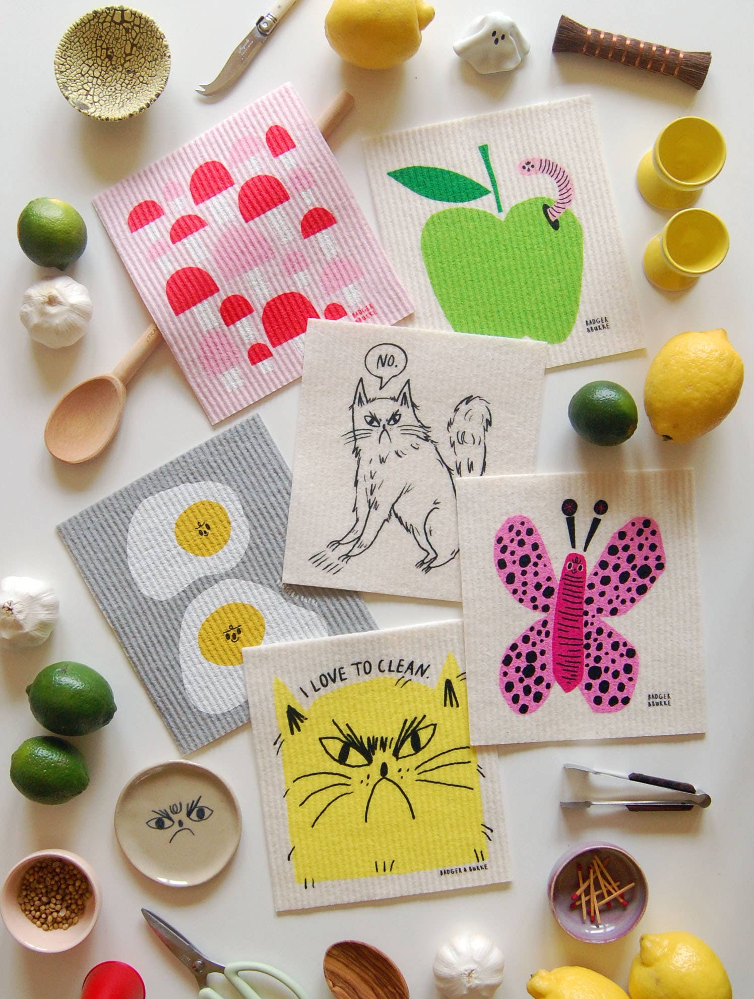 Set of colorful dishcloths with various designs on a white surface with kitchen items.