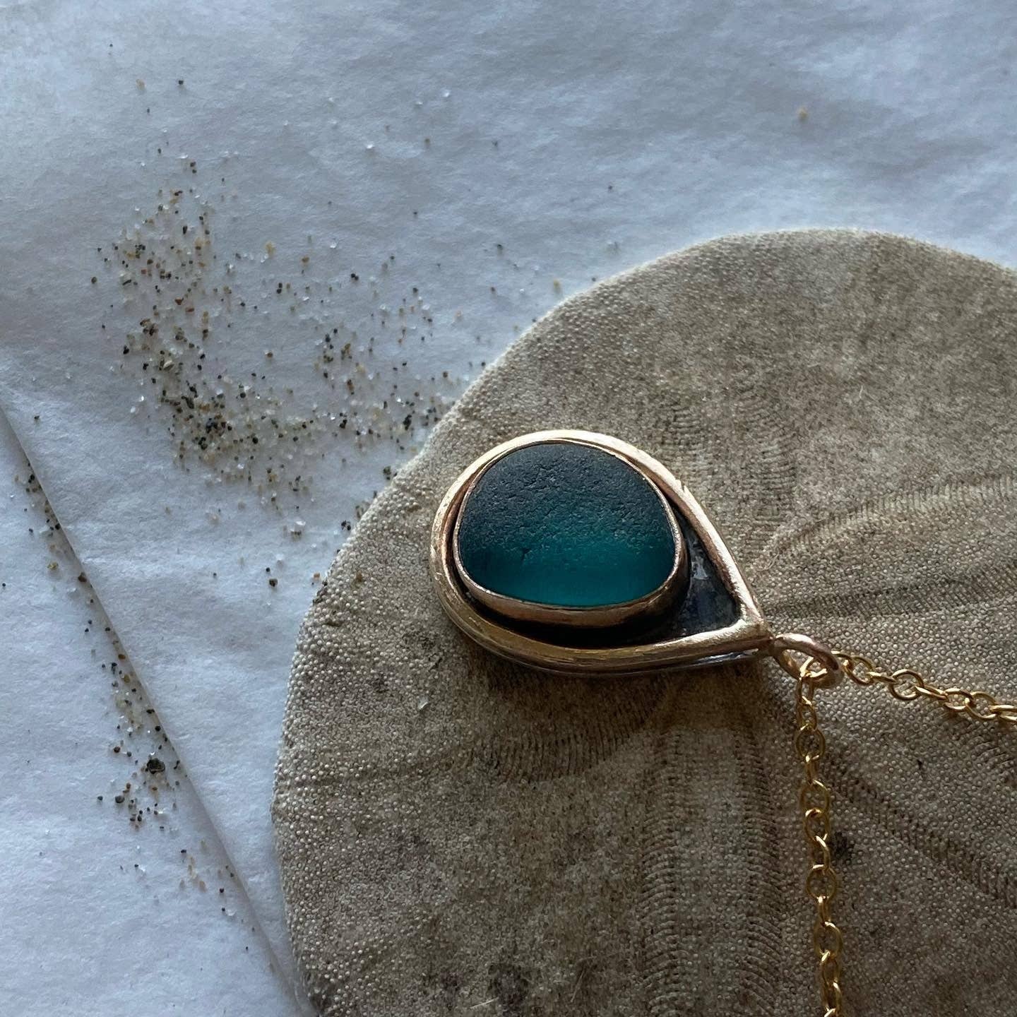 Stylish display of the Mermaid Tear Necklace showcasing its one-of-a-kind sea glass design and elegant gold accents.