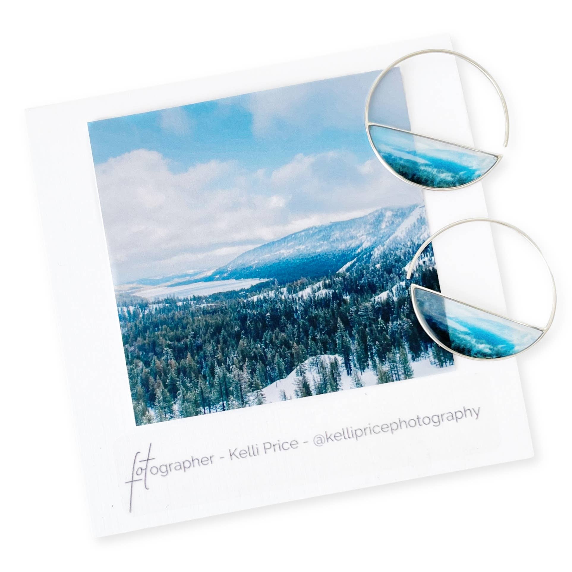 Tahoe Snow Earrings by Foterra Jewelry displayed alongside a scenic photograph of snowy mountains, highlighting their elegant, modern hoop design and lightweight feel.