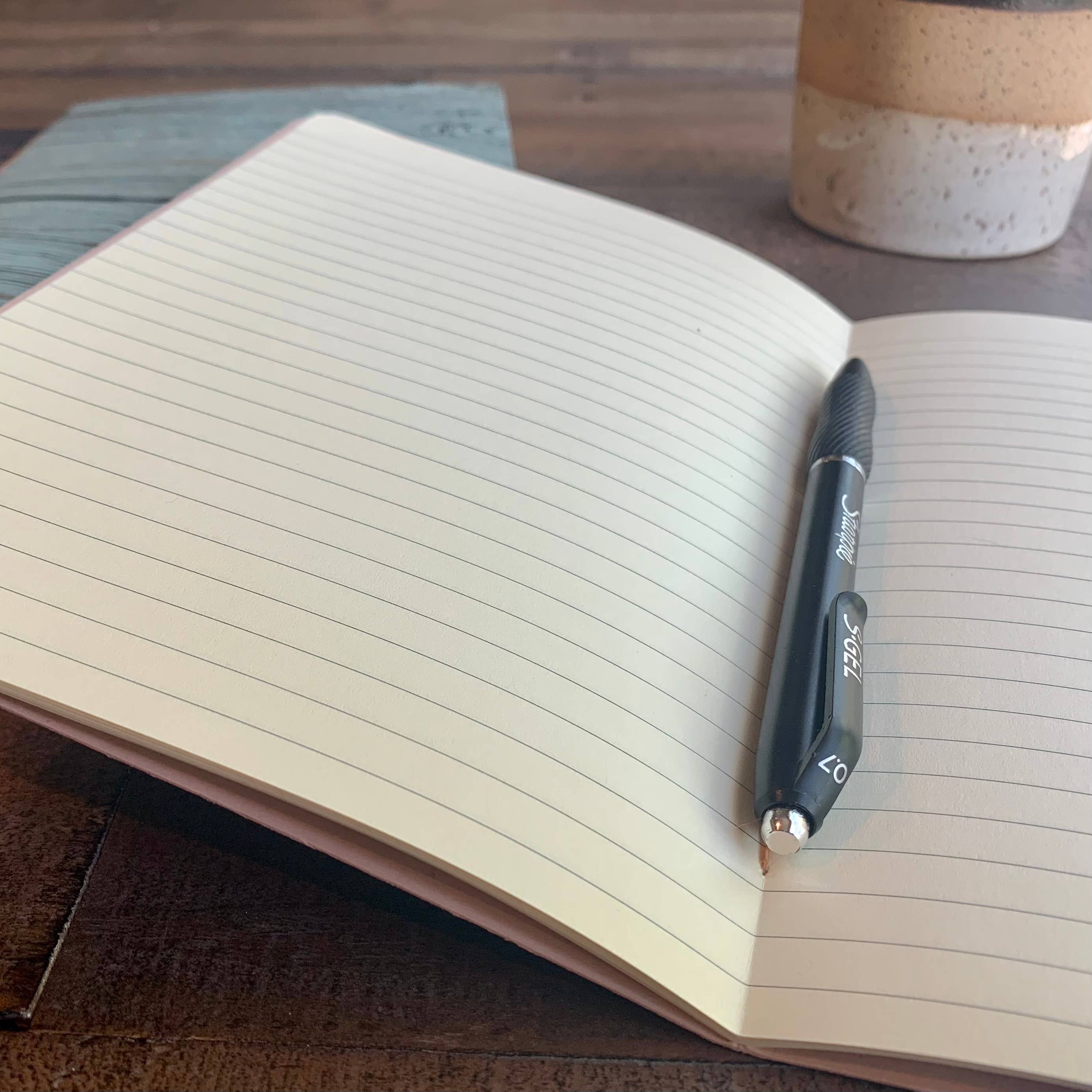 Softcover Notebook by The Casual Bookbinder on a wooden surface, with a lined interior and a black pen, compliments casual writing.