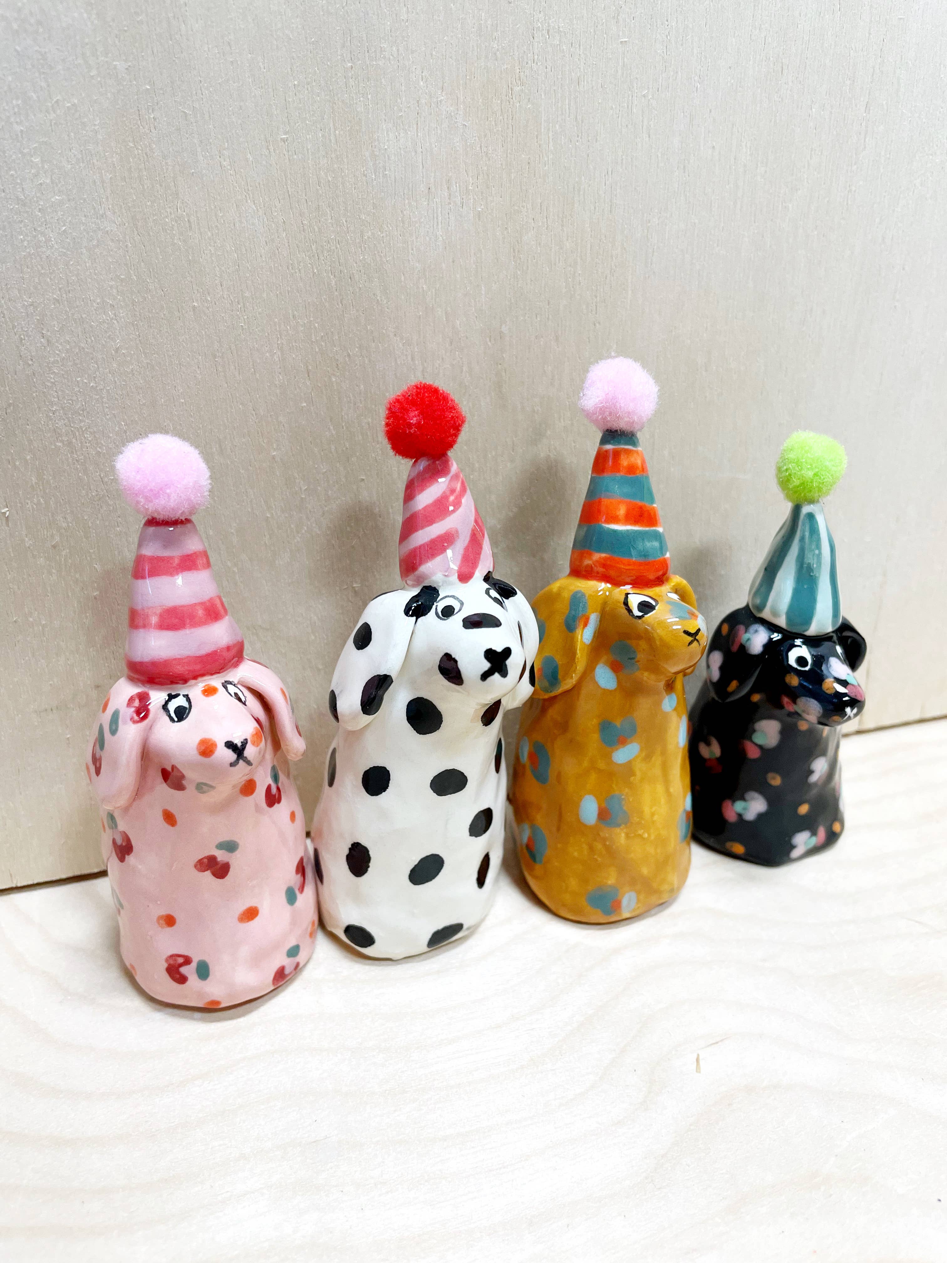 Colorful collection of mini party dogs in party hats, handcrafted by Bianca Rae, featuring playful designs with polka dots and stripes, titled 'Party Minis!'