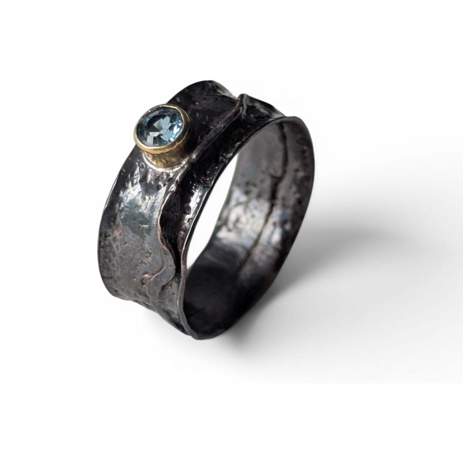 Folded copper ring with faceted blue sapphire by Deb Collins, showcasing unique handmade jewelry inspired by natural shapes.