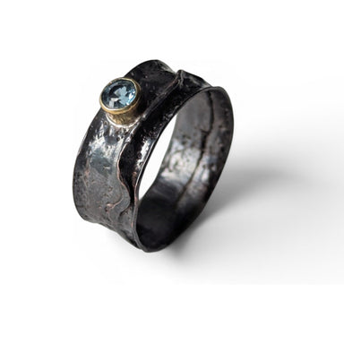 Folded copper ring with faceted blue sapphire by Deb Collins, showcasing unique handmade jewelry inspired by natural shapes.