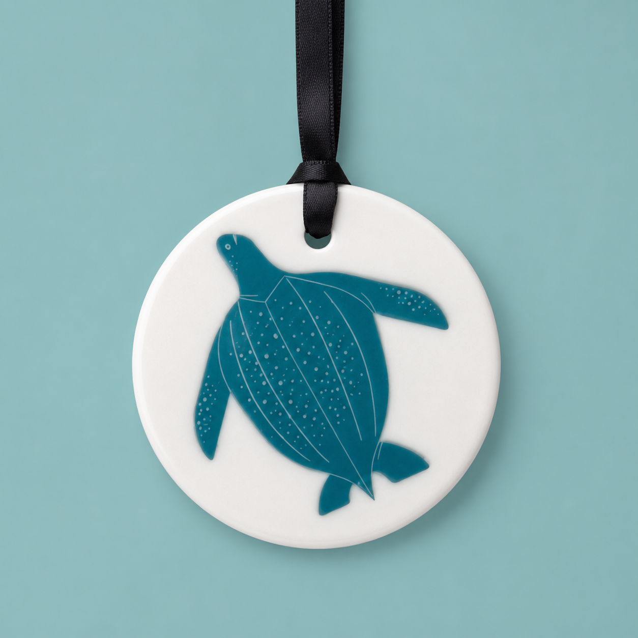 Round ceramic ornament with a blue turtle design on a white background