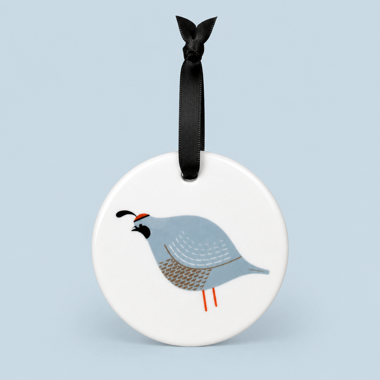 Round ceramic ornament with a bird design on a white background