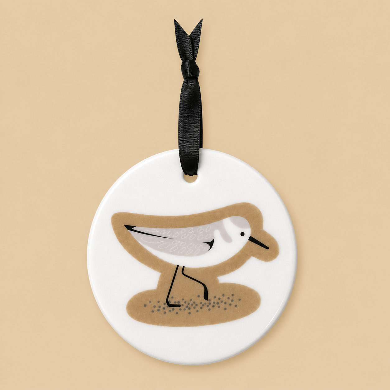 Round ceramic ornament with a sandpiper design on a beige background