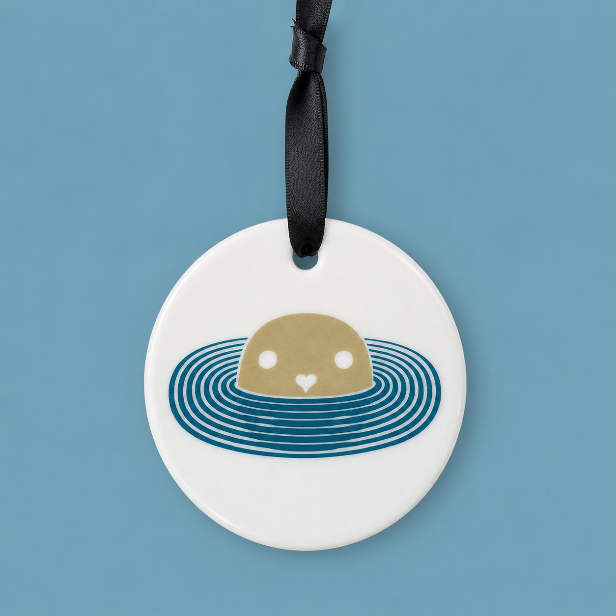 Round white ceramic tag with a brown bear illustration in water, hanging on a black ribbon against a blue background.