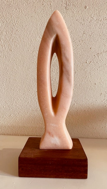 Stone sculpture titled 'Harmony' by Hearts for the Arts, crafted from Portuguese rosa marble, featuring an elegant design on a hardwood base, measuring 11" x 4" x 4".