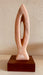 Stone sculpture titled 'Harmony' by Hearts for the Arts, crafted from Portuguese rosa marble, featuring an elegant design on a hardwood base, measuring 11" x 4" x 4".
