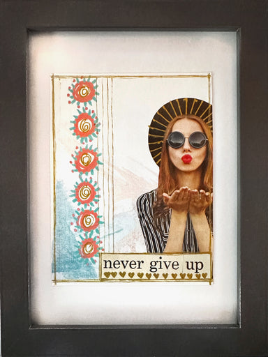 Framed mixed media collage titled 'Never Give Up' by Hearts for the Arts, featuring a stylish woman in sunglasses blowing kisses, surrounded by artistic elements and inspirational text.