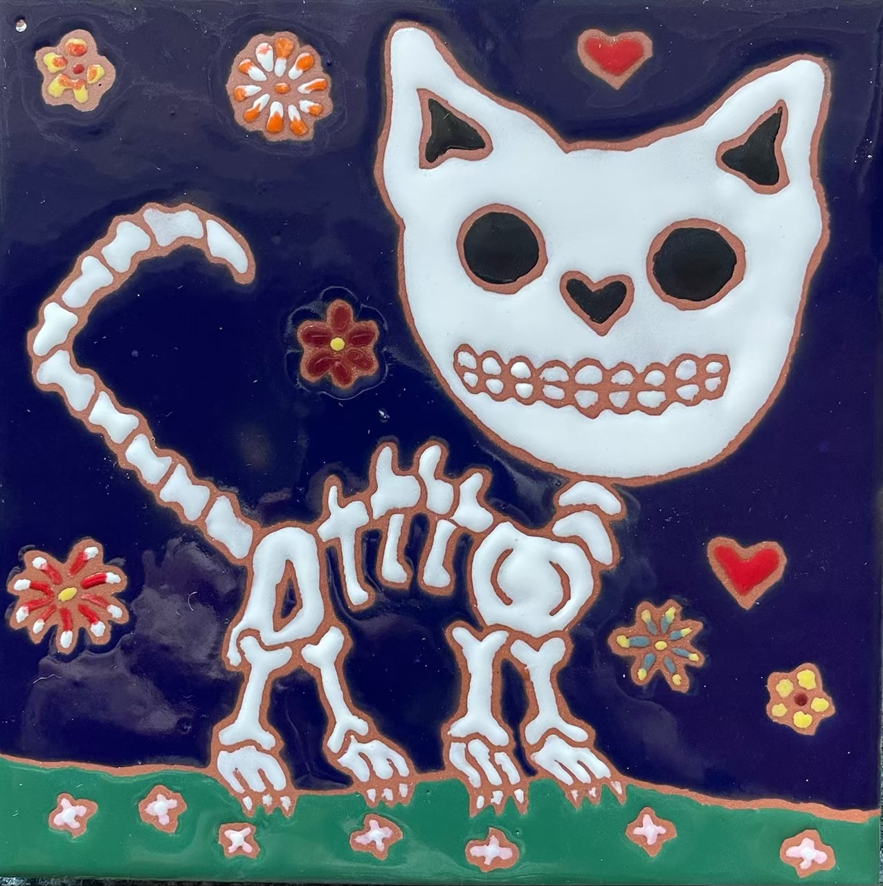 Ceramic tile featuring a whimsical skeleton cat design with a heart motif and colorful floral accents, created by Hearts for the Arts as part of the Hearts for the Arts | 2 Tiles collection.