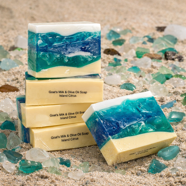 Handcrafted Ocean Soap by The Grecian Soap Company displayed on sandy beach with ocean wave design and Island Citrus scent.