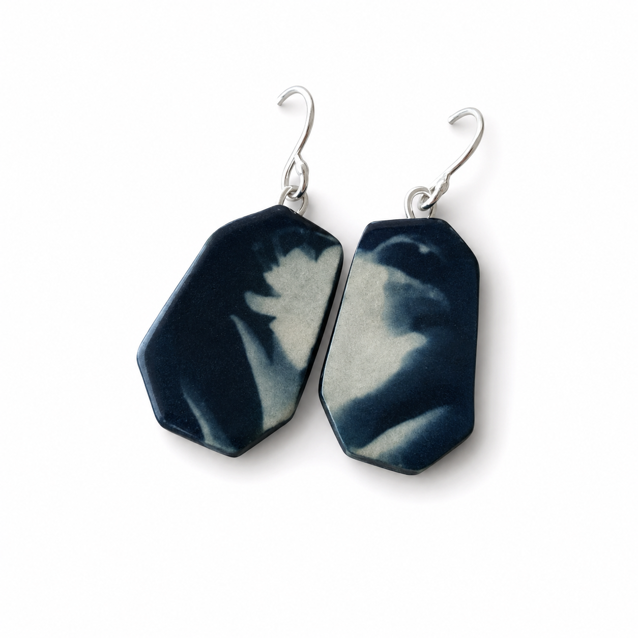 A pair of drop earrings with irregular hexagonal dark blue and white marbled stone pendants on silver-tone hooks, shown on a plain white background.