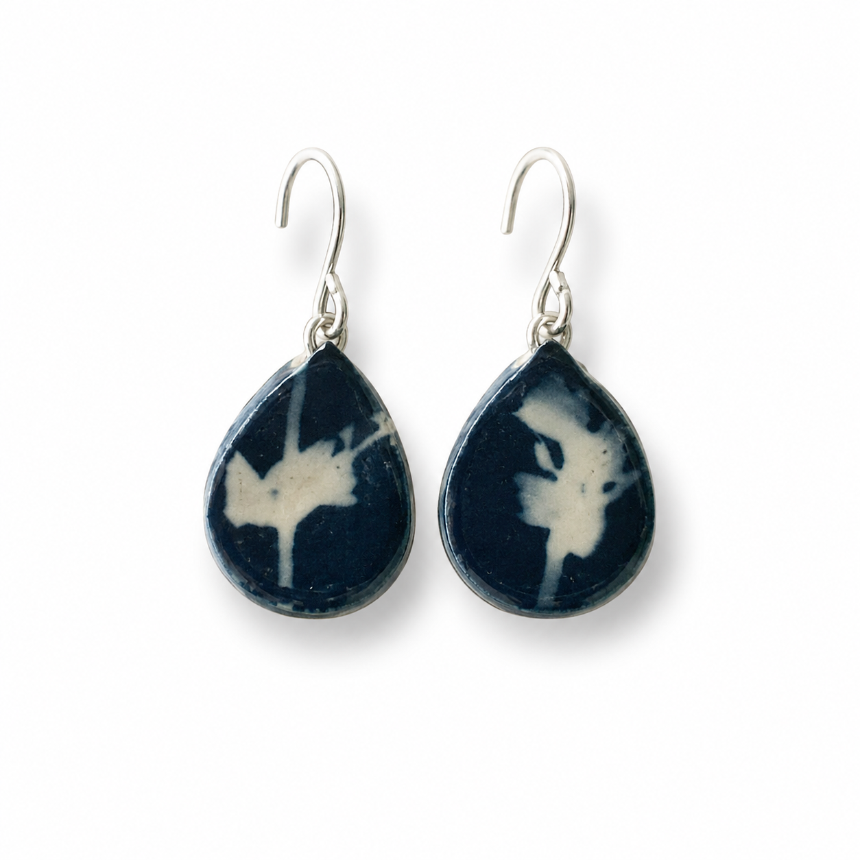 A pair of teardrop-shaped drop earrings featuring dark navy blue and white marbled stone inlays with silver-toned fishhook wires, shown against a plain white background.