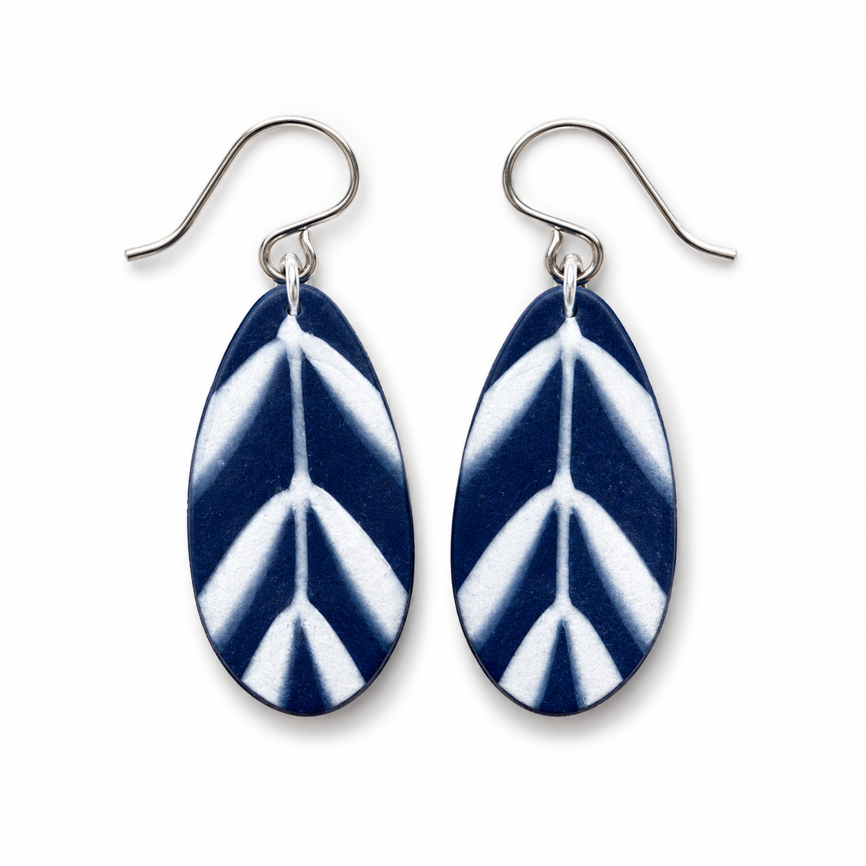 A pair of teardrop-shaped drop earrings with a navy blue and white leaf pattern, suspended from silver fishhook wires on a plain white background.