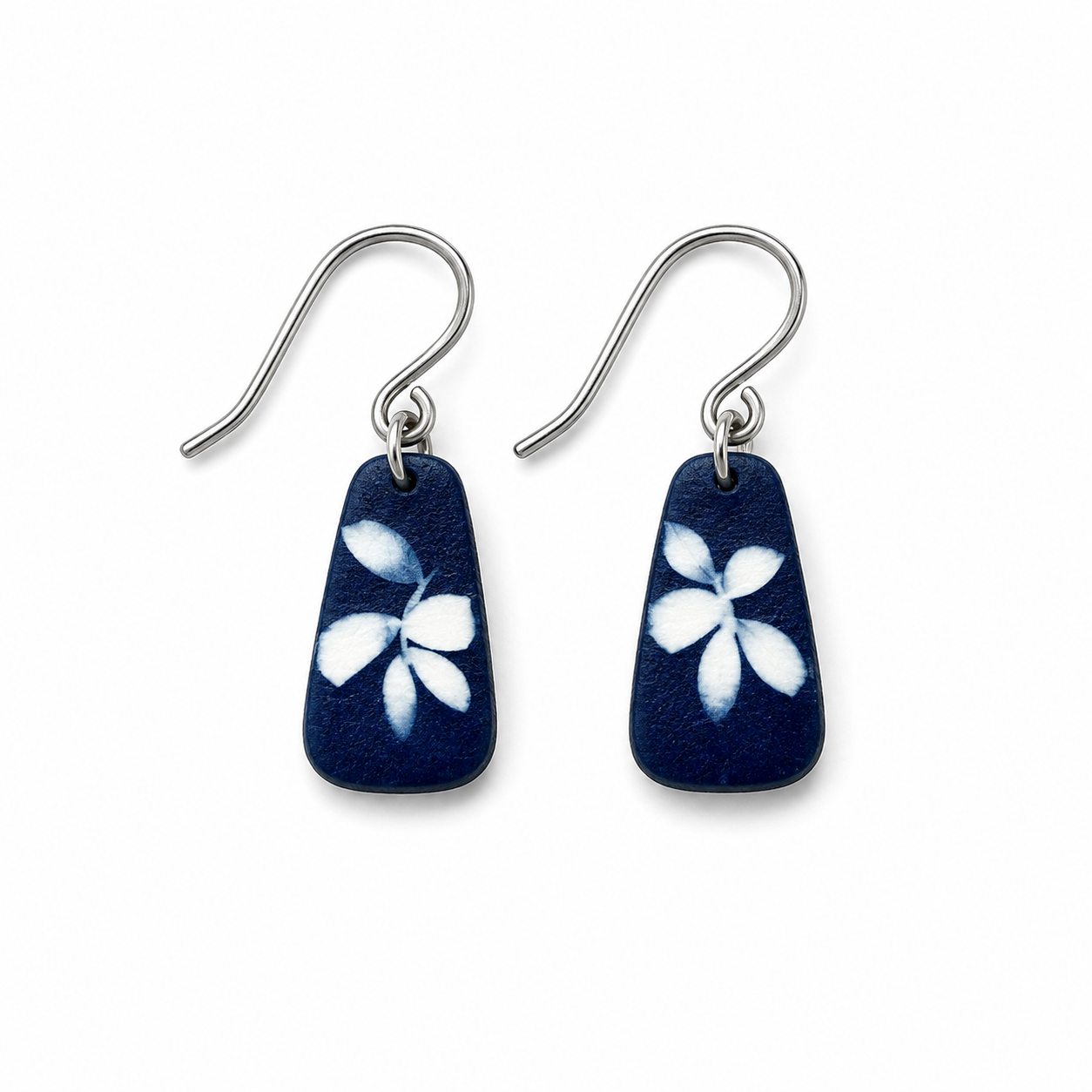 A pair of silver-tone dangle earrings with dark navy blue teardrop-shaped charms featuring a white hand-painted flower motif, shown on a plain white background.
